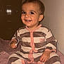 toddler, child, smiling, striped_onesie, indoor, soft_towel, brown_stripes, cream_stripes, pink_trim, happy, cute, sitting, baby, face, person, portrait, cozy, warm_lighting, floor, blanket