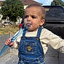 Aurélien a rejoint le concours — aidez-le/la à gagner de superbes lots ! toddler, child, denim_overalls, blue_fork, outdoor, daylight, curious, vehicle, tree, sky, face, person, casual_clothing, young_child, expression, playful, holding_object, nature, jeans, portrait