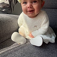 Louna participe au concours pour gagner de l'argent avec cette photo : baby, child, smiling, flower_crown, white_sweater, couch, indoor, portrait, happy, cute, infant, soft_lighting, cozy, toddler, seated, headwear, fabric, skin, person, home