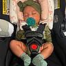 baby, infant, car_seat, pacifier, headband, sleeping, green_clothing, socks, safety_harness, pink_cushions, child, newborn, seatbelt, resting, adorable, cute, indoors, infant_care, transportation_safety, small_person