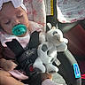 baby, child, car_seat, pacifier, headband, sleeping, toy, stuffed_animal, blanket, pink_clothing, socks, seatbelt, car_interior, sunlight, peaceful, infant, cute, cozy, soft_toy, resting