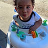 Kobe is registered to the contest to win money with this photo: toddler, baby, walker, curly_hair, outdoor, toy, colorful, shirt, face, child, play, sunlight, concrete, expression, person, young, cute, curious, small, white