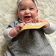 Bianca a rejoint le concours — aidez-le/la à gagner de superbes lots ! baby, blue_eyes, card, child, closeup, cute, fluffy_background, gray_dress, hands, happy, headband, indoor, infant, joyful, lying_down, person, playful, portrait, smile, white_sleeves