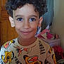 child, boy, curly_hair, smiling, shirt, lion_king, indoor, wardrobe, clothing, furniture, face, person, portrait, happy, young, cute, room, casual, colorful, hair