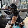 dog, pet, clothing, vest, hoodie, car_interior, blanket, snowman_pattern, window, chain_link_fence, seat, side_mirror, brown_fur, black_fur, attentive, indoor, animal, cozy, winter_wear, profile_view