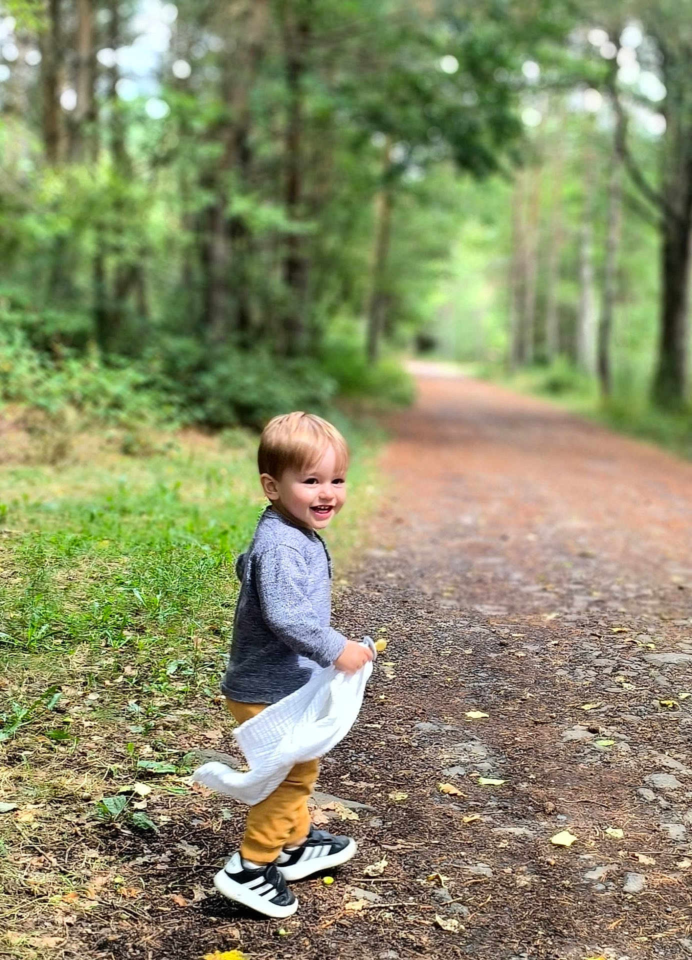 Louka Seguet participe au concours pour gagner de l'argent avec cette photo : casual, child, clothing, daylight, dirt_path, forest, greenery, happy, leaves, nature, outdoor, path, playful, smiling, sneakers, toddler, trees, walking, white_cloth, young_child