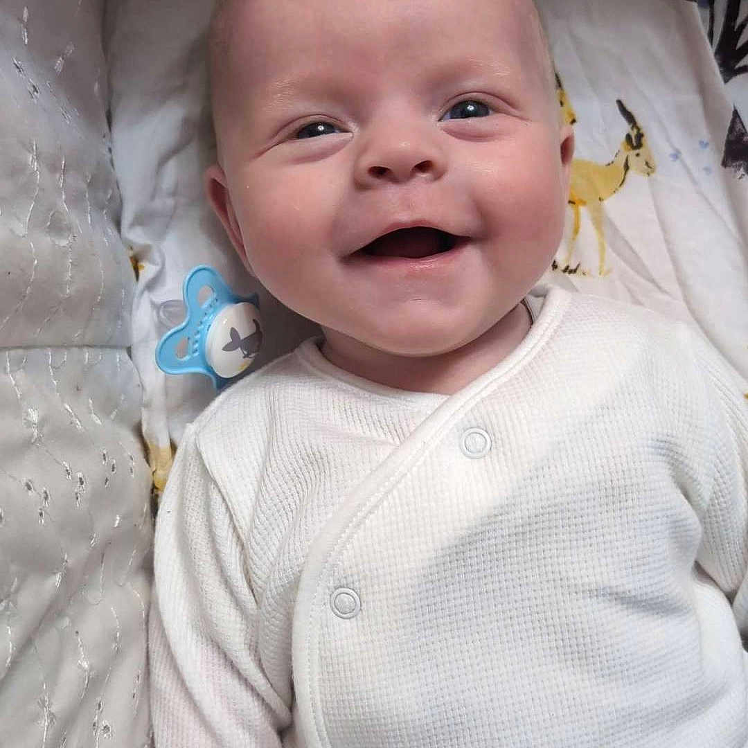 Arthŵr is registered to the contest to win money with this photo: accessories, baby, babylaughing, bed, face, furniture, happy, head, jewelry, necklace, newborn, person, photography, portrait, smile