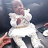 adorable, baby, black_leather_couch, child, curious, cute, frilly_skirt, hand, human, indoor, infant, patterned_leggings, person, phone, portrait, sitting, small_baby, socks, white_clothing, young_child