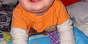Eduardo joined the competition — help win amazing prizes! baby, child, smiling, orange_shirt, blanket, indoor, portrait, face, hands, happy, cute, toddler, colorful, clothing, bedroom, crawling, infant, long_sleeve, young_child, playful