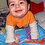 baby, child, smiling, orange_shirt, blanket, indoor, portrait, face, hands, happy, cute, toddler, colorful, clothing, bedroom, crawling, infant, long_sleeve, young_child, playful