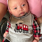 Malakai is registered to the contest to win money with this photo: baby, child, knitted_vest, train_design, plaid_shirt, person, arm, pink_shirt, seated, indoor, face, blue_eyes, casual_clothing, cute, infant, portrait, hand, fabric, closeup, skin