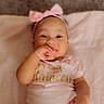 baby, blanket, child, cute, fingers, hand, happy, headband, indoors, infant, lying_down, person, pink_bow, portrait, princess, shirt, smiling, soft, text, young