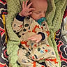 newborn, baby, infant, sleeping, pacifier, onesie, fox_pattern, blanket, green_blanket, stroller, car_seat, seated, hand, portrait, close_up, indoors, cozy, textile, colorful, nap