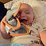 Josef is registered to the contest to win money with this photo: baby, bed, blanket, child, cozy, dinosaur_pattern, face, hand, indoor, infant, laughing, lying_down, nursery, pajamas, photography, pillow, plush_toy, portrait, smiling, stuffed_toy