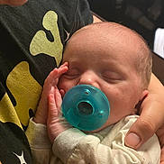 Josef joined the competition — help win amazing prizes! newborn, baby, infant, sleeping, pacifier, cuddled, adult, hand, face, portrait, close_up, indoors, family, caregiving, onesie, clothing, soft_lighting, relaxed, tender, photography
