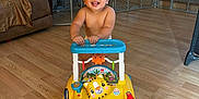 Liam joined the competition — help win amazing prizes! toddler, child, walker_toy, smiling, indoor, living_room, wooden_floor, curly_hair, happy, baby, play_area, furniture, couch, toy, person, flooring, childhood, home, cute, exploring