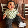 toddler, child, smiling, curly_hair, checkered_shirt, black_pants, white_sneakers, wooden_chair, metal_chair, wooden_wall, indoor, happy, sitting, cute, portrait, person, fashion, casual, looking_up, young_child