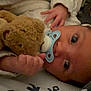 baby, teddy_bear, pacifier, blanket, hand, face, infant, sleepwear, close_up, cute, child, soft_toy, lying_down, indoors, newborn, person, comfort, resting, warm, cozy