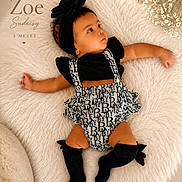 Zoe is registered to the contest to win money with this photo: baby, infant, girl, black_headband, flower_headband, black_top, patterned_overalls, knee_high_socks, fluffy_rug, white_rug, lying_down, cute, portrait, flowers, decor, soft_texture, newborn, child, adorable, studio_photo