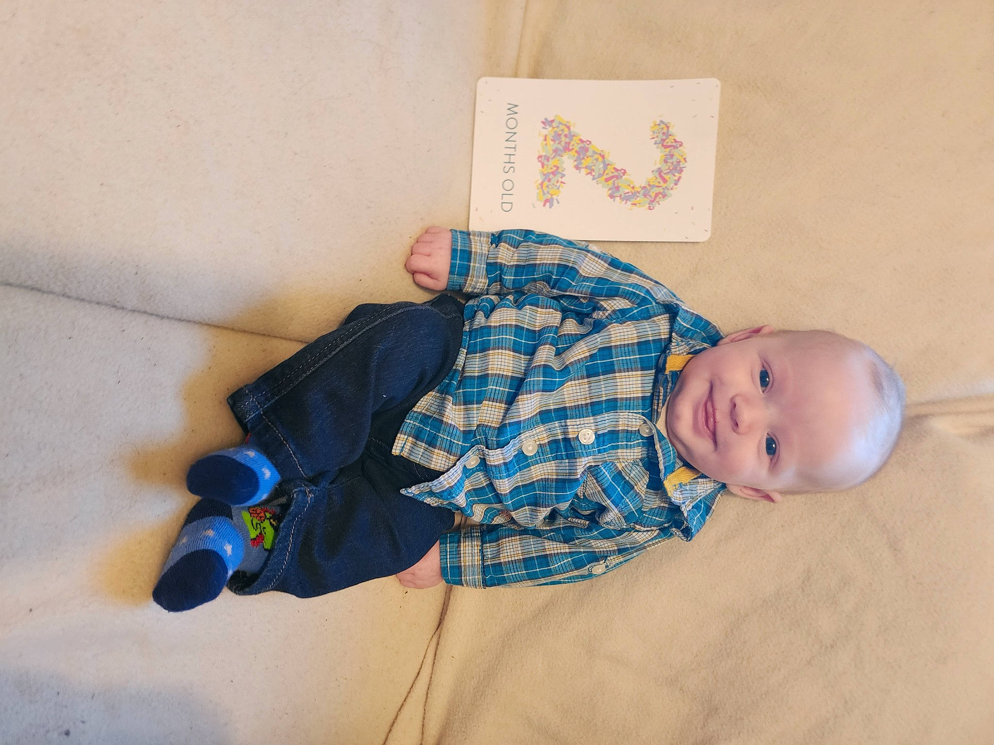 Bryson is registered to the contest to win money with this photo: baby, baby_products, baby_toddler_clothing, bedtime, child, comfort, electric_blue, fashion_accessory, flooring, joy, linens, paper_product, pattern, person, plaid, room, sitting, sleeve, toddler, wood