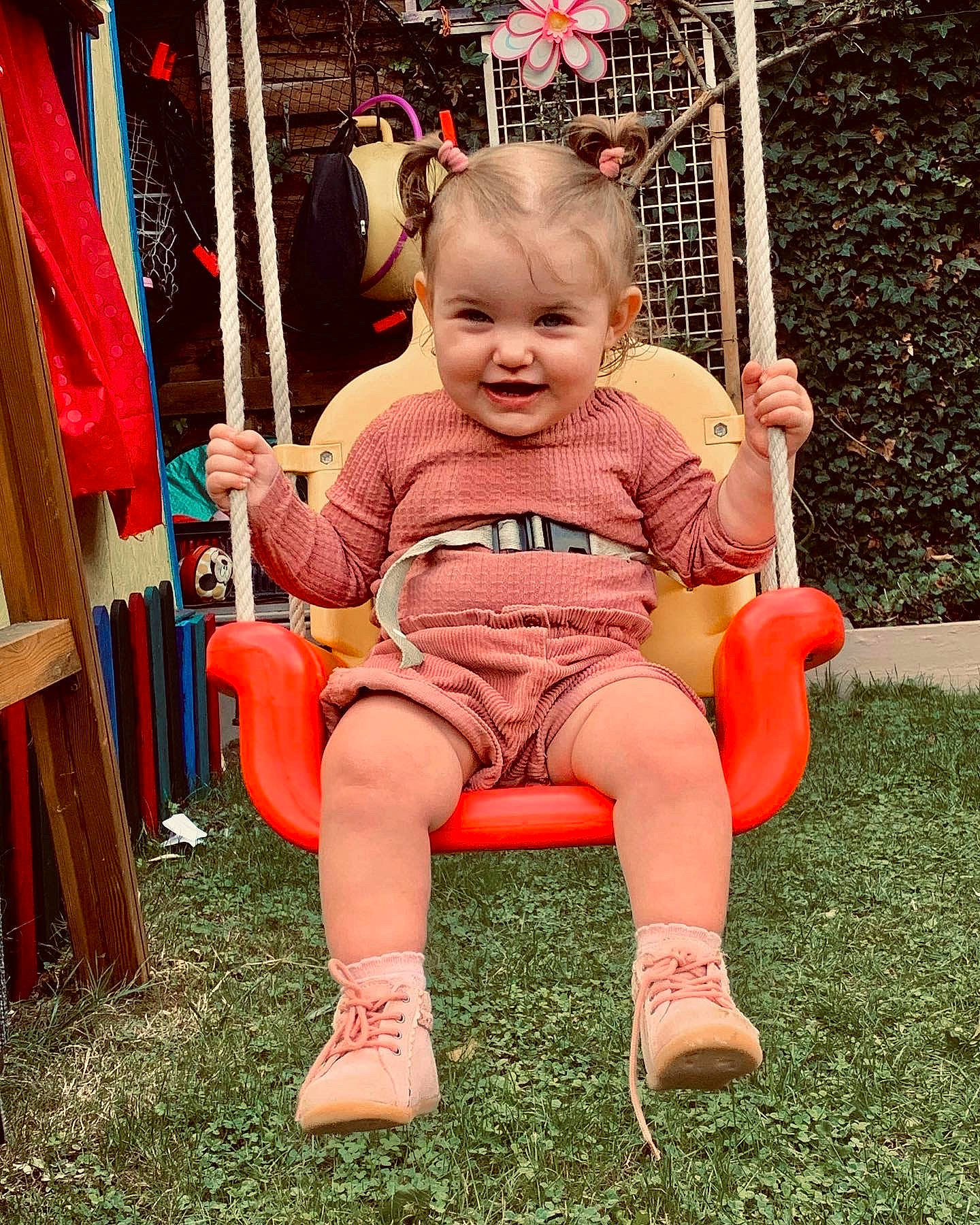 Clara a rejoint le concours — aidez-le/la à gagner de superbes lots ! baby, baby_toddler_clothing, chair, child, event, fun, grass, happy, joy, lap, leisure, outdoor_play_equipment, people, person, pink, recreation, red, shoe, shorts, sitting