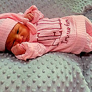 Florence is registered to the contest to win money with this photo: newborn, baby, pink_clothing, hat, blanket, infant, lying_down, soft_texture, cute, small_hands, peaceful, wrapped, cozy, portrait, indoors, sleepy, child, toddler, soft_lighting, resting