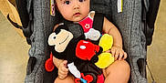 Kayla joined the competition — help win amazing prizes! baby, car_seat, plush_toy, mickey_mouse, indoor, child, infant, toy, footwear, floor, straps, seat, pink_clothing, red, yellow, black, white, curious, sitting, childcare