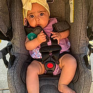 Kayla joined the competition — help win amazing prizes! baby, child, car_seat, seatbelt, pacifier, headband, clothing, purple_outfit, legs, feet, hands, expression, indoors, safety, infant, cute, portrait, person, closeup, seat