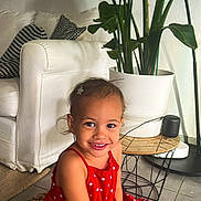 Lyah a rejoint le concours — aidez-le/la à gagner de superbes lots ! child, girl, red_dress, polka_dot, smile, hair_clip, sitting, pouf, knitted, couch, pillows, plant, indoor, floor, table, pot, happy, cute, home, decor