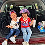 beverage, car, casual_clothing, child, children, cup, daytime, friendship, happy, hat, jeans, outdoor, peace_sign, red_shirt, sitting, smile, snacks, sneakers, trunk, white_shirt