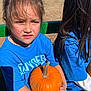 Zoey-Ann is registered to the contest to win money with this photo: bench, blue_shirt, casual_clothing, child, daytime, expression, fall, field, grass, hair, harvest, holding, nature, outdoor, person, pumpkin, sitting, sunlight, two_people, young