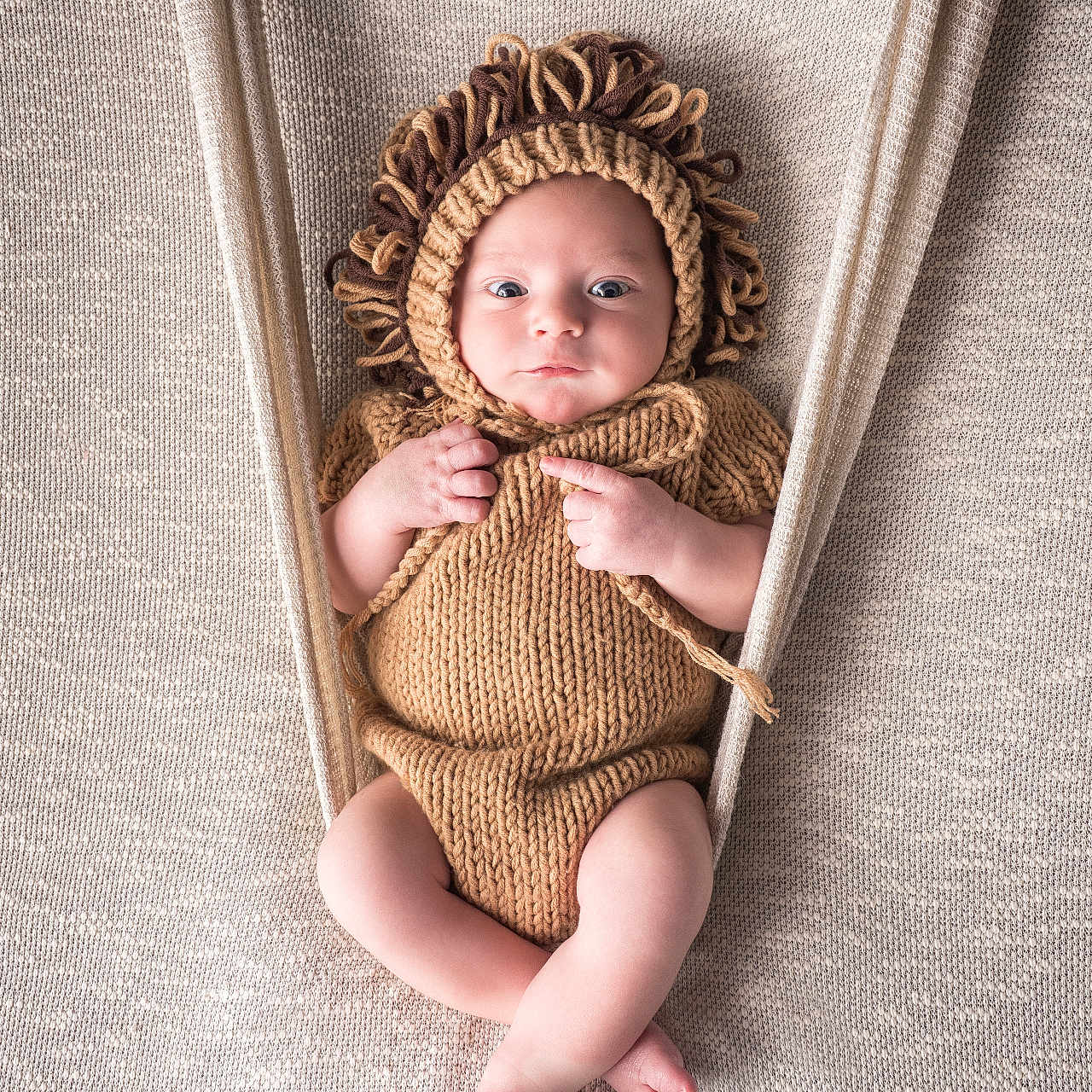 Pablo a rejoint le concours — aidez-le/la à gagner de superbes lots ! baby, baby_clothing, baby_pose, background, beige, child, comfortable, cozy, cute, fabric, hammock, hand_knitted, infant, knitted, lion_costume, newborn, portrait, resting, soft_texture, wide_eyes
