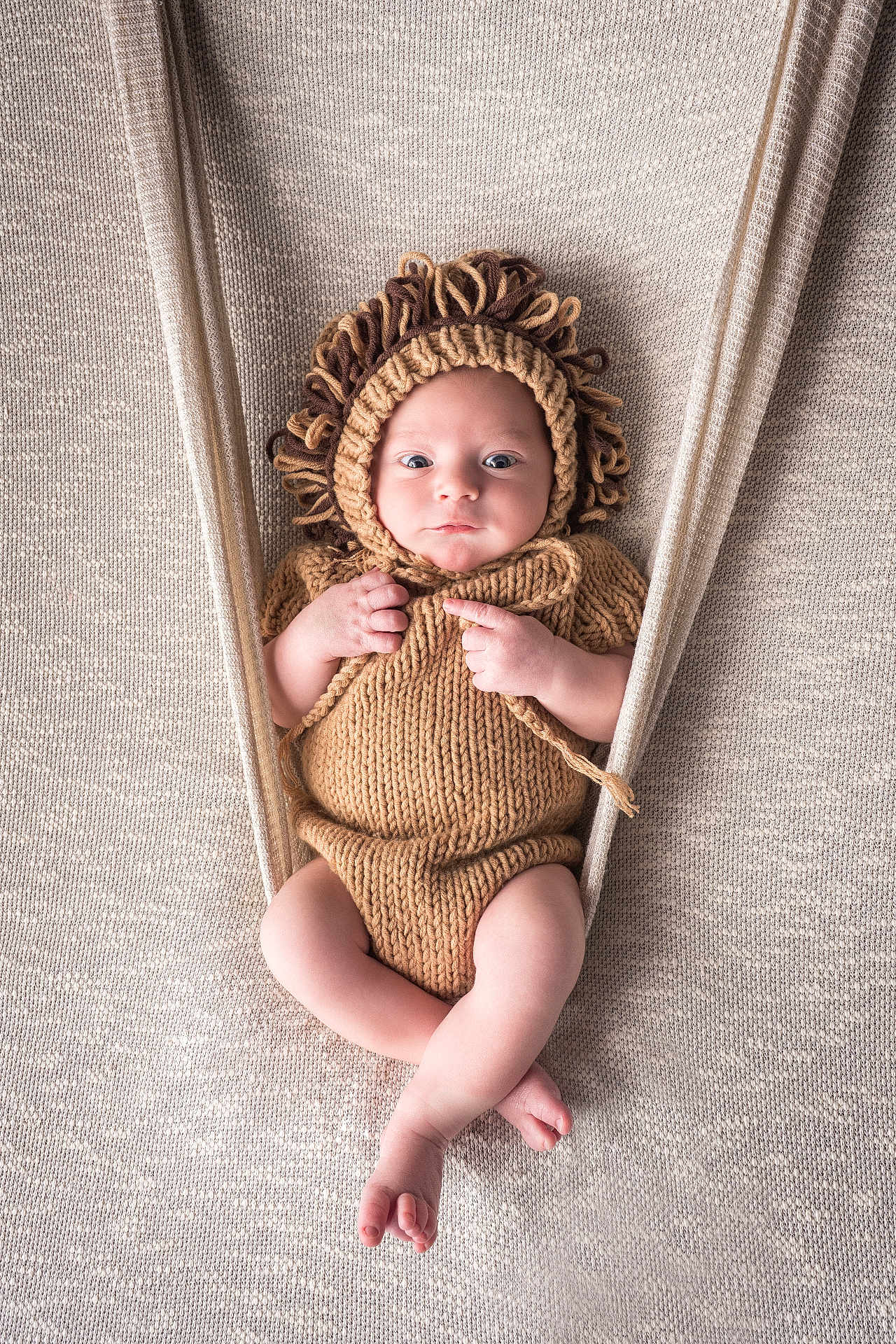 Pablo a rejoint le concours — aidez-le/la à gagner de superbes lots ! baby, infant, knitted, lion_costume, hammock, beige, soft_texture, cute, portrait, wide_eyes, baby_clothing, hand_knitted, cozy, comfortable, newborn, child, resting, fabric, background, baby_pose