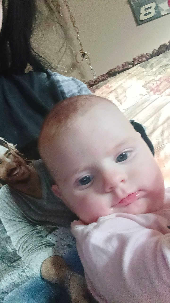 Roselynn joined the competition — help win amazing prizes! baby, infant, child, close_up, selfie, portrait, indoor, couch, blanket, drool, pink_clothing, eyes, mouth, adult_torso, printed_tshirt, hair, necklace, wall_art, pillow, relaxed