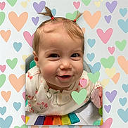Darla is registered to the contest to win money with this photo: baby, child, smiling, pigtails, activity_center, colorful, heart_pattern, cute, infant, playful, portrait, indoors, happy, young_child, face, clothing, toy, closeup, cheerful, person