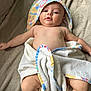 baby, infant, towel, blanket, skin, face, head, legs, arms, lying_down, soft_texture, comfort, colorful, patterned_towel, cute, chubby, indoors, relaxed, child, person