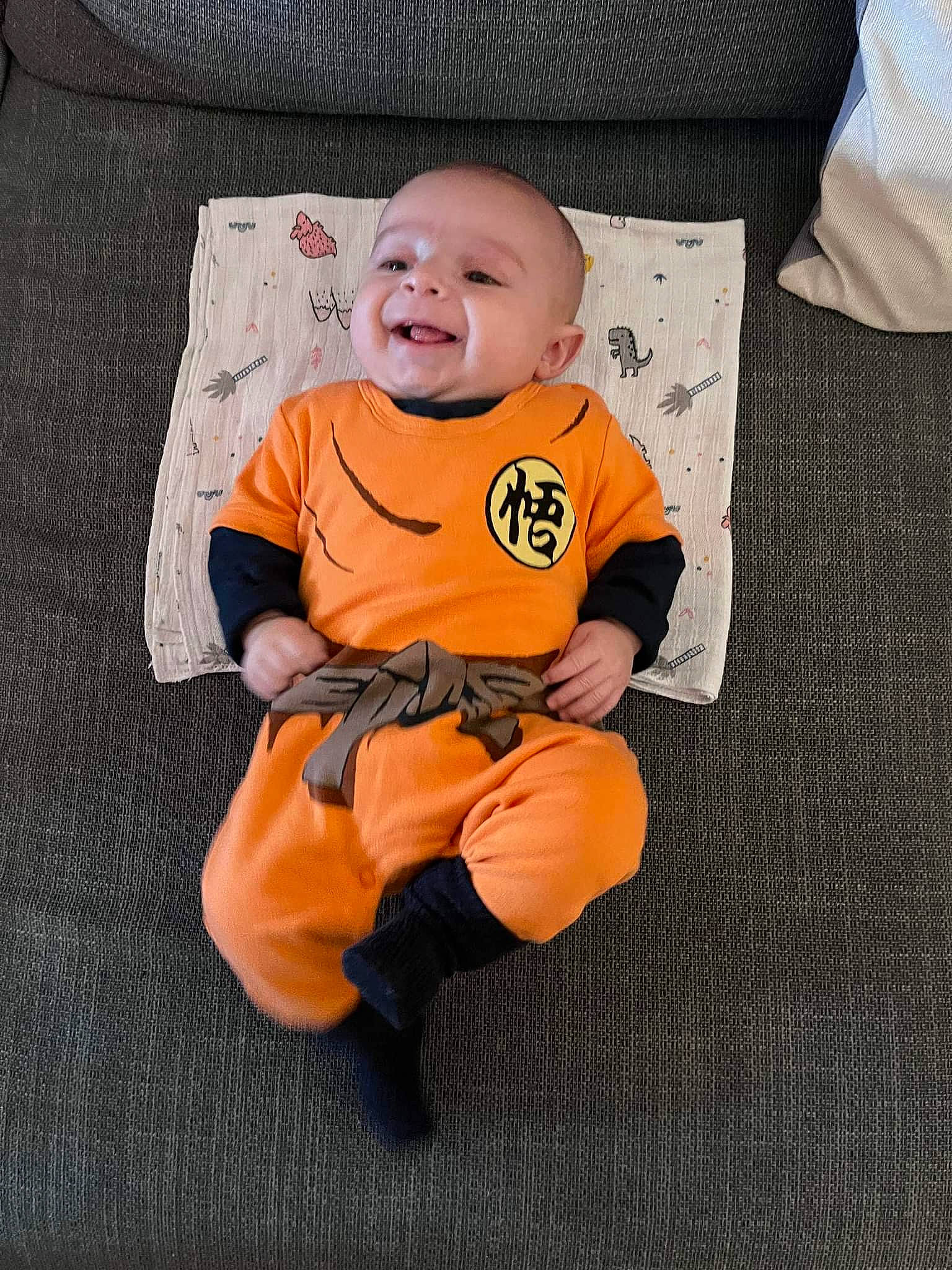 Sevan participe au concours pour gagner de l'argent avec cette photo : baby, baby_products, baby_toddler_clothing, child, comfort, eye, face, flooring, grey, head, linens, orange, pattern, person, pillow, sitting, sleeve, smile, t_shirt, toddler