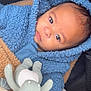 baby, blue_hoodie, stuffed_toy, blanket, stroller, child, face, portrait, cozy, infant, cute, soft_toy, warm_clothing, fuzzy_texture, looking, small_hands, indoors, comfortable, young_child, casual