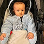 baby, child, hooded_jacket, blanket, stroller, hand, face, person, blue, coat, infant, young_child, seated, brush, curious, indoors, clothing, warm, cute, portrait