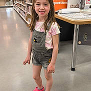 Théa a rejoint le concours — aidez-le/la à gagner de superbes lots ! child, girl, smile, standing, denim_overalls, pink_clogs, sunglasses, store_aisle, floor, display_table, shelves, clothing, shorts, casual_wear, retail, happy, indoor, person, footwear, young