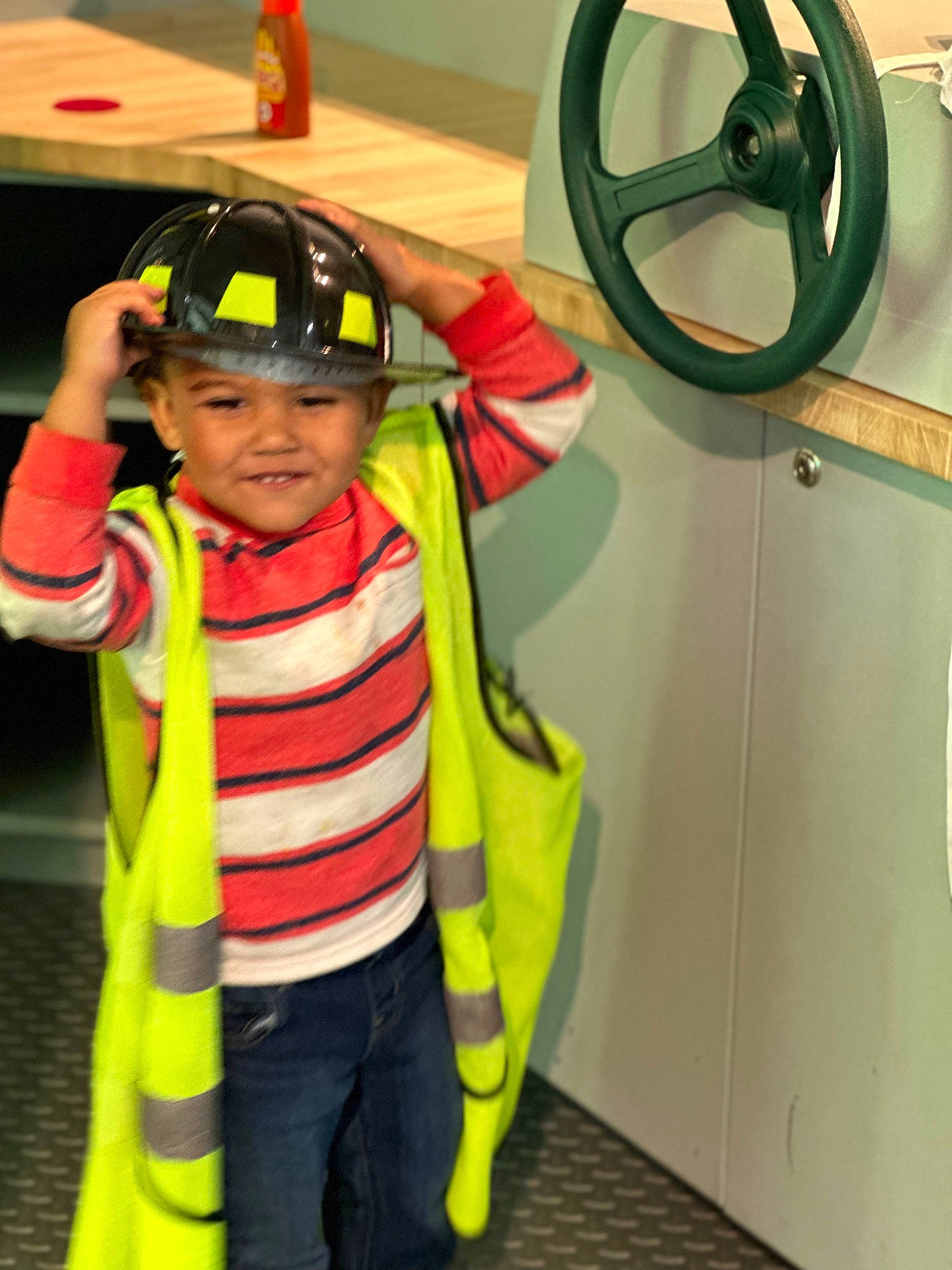 Jaxton is registered to the contest to win money with this photo: child, costume, door, fictional_character, fun, gas, gesture, happy, headwear, high_visibility_clothing, joy, leisure, lifejacket, person, personal_protective_equipment, room, sleeve, smile, t_shirt, toddler