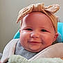 baby, child, smiling, headband, bow, teddy_bear, plush_toy, cute, portrait, indoor, soft_toy, happy, infant, seated, clothing, striped_shirt, furniture, baby_carrier, face, closeup