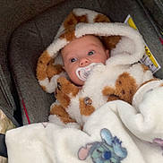 Giuliana participe au concours pour gagner de l'argent avec cette photo : baby, pacifier, blanket, stroller, hooded_outfit, fur_texture, cartoon_character, sleepy_face, cozy, child, infant, cute, soft, warm, outdoor, bundle, clothing, portrait, face, babywear