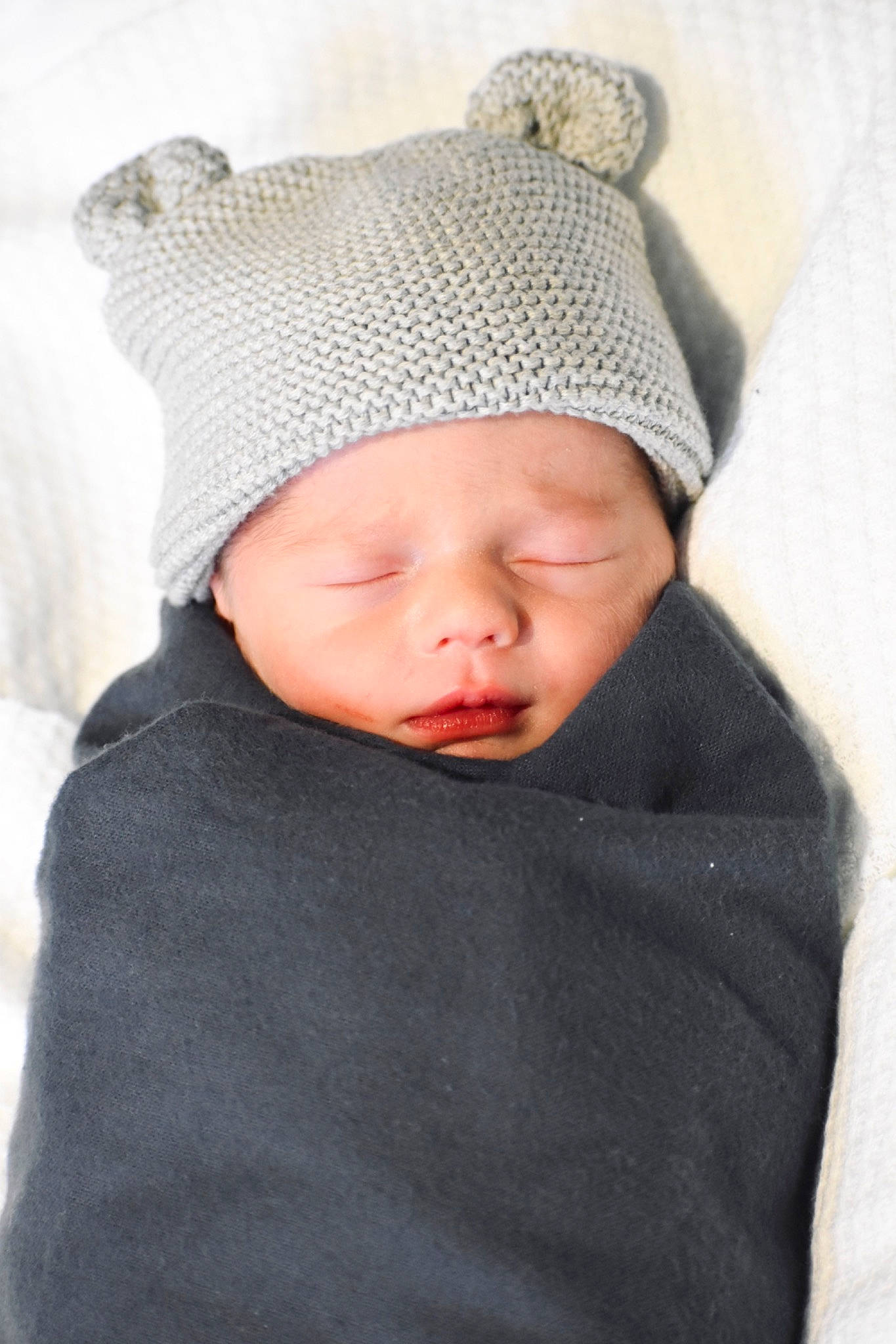 Damon is registered to the contest to win money with this photo: baby, baby_toddler_clothing, beanie, cap, cheek, collar, comfort, face, fashion_accessory, grey, headgear, headwear, knit_cap, outerwear, pattern, person, sitting, sleeve, toddler, winter