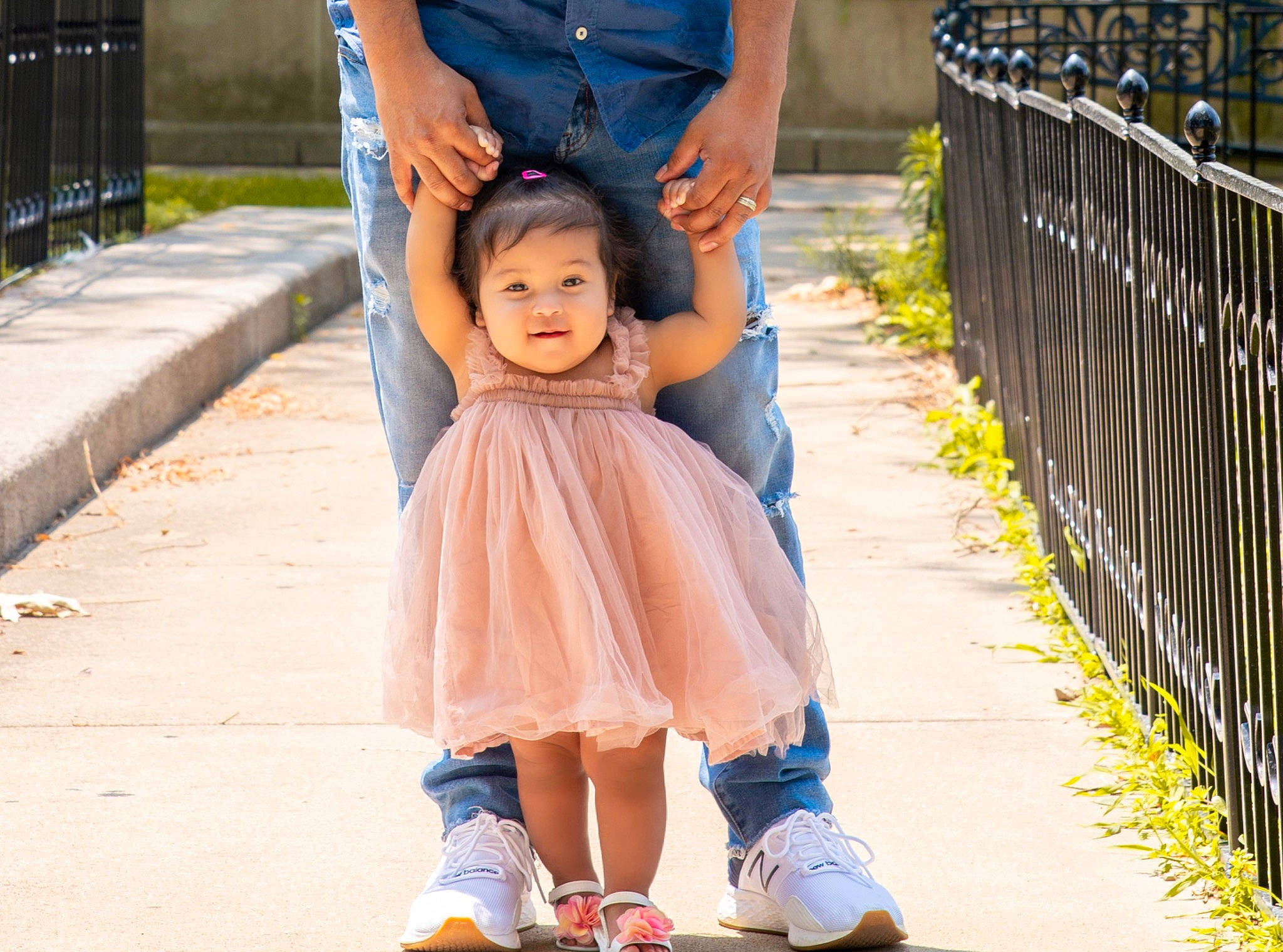 Samaria is registered to the contest to win money with this photo: baby, child, dress, electric_blue, fence, footwear, gesture, grass, happy, leg, leisure, people, person, photograph, plant, recreation, shoe, smile, sneakers, standing