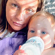 Belladonna June joined the competition — help win amazing prizes! adult, baby, bottle, feeding, close_up, blue_eyes, sunlight, shadow_stripes, purple_sweatshirt, lip_piercing, hair, couch, home, relaxing, portrait, face, hand, skin, eyes, infant
