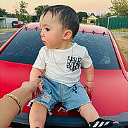 Thiago Gael is registered to the contest to win money with this photo: adult_hand, black_sandals, casual_clothing, child, curious, denim_shorts, footwear, gold_bracelet, holding_hand, necklace, outdoor, red_car, shorts, side_view, street, suburban, summer, sunset, toddler, white_tshirt