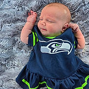 Oakleigh is registered to the contest to win money with this photo: baby, infant, child, sleeping, lying_down, portrait, face, arms, sports_outfit, football_jersey, navy_blue, neon_green, blanket, fuzzy_blanket, indoor, close_up, peaceful, cute, seahawks_logo, photography