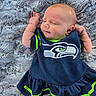 baby, infant, child, sleeping, lying_down, portrait, face, arms, sports_outfit, football_jersey, navy_blue, neon_green, blanket, fuzzy_blanket, indoor, close_up, peaceful, cute, seahawks_logo, photography