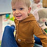 Michael is registered to the contest to win money with this photo: child, toddler, boy, hoodie, brown_clothing, smiling, face, person, indoor, plush_toy, elephant_toy, blurred_background, happy, casual_clothing, portrait, young_child, playful, candid, cute, jeans